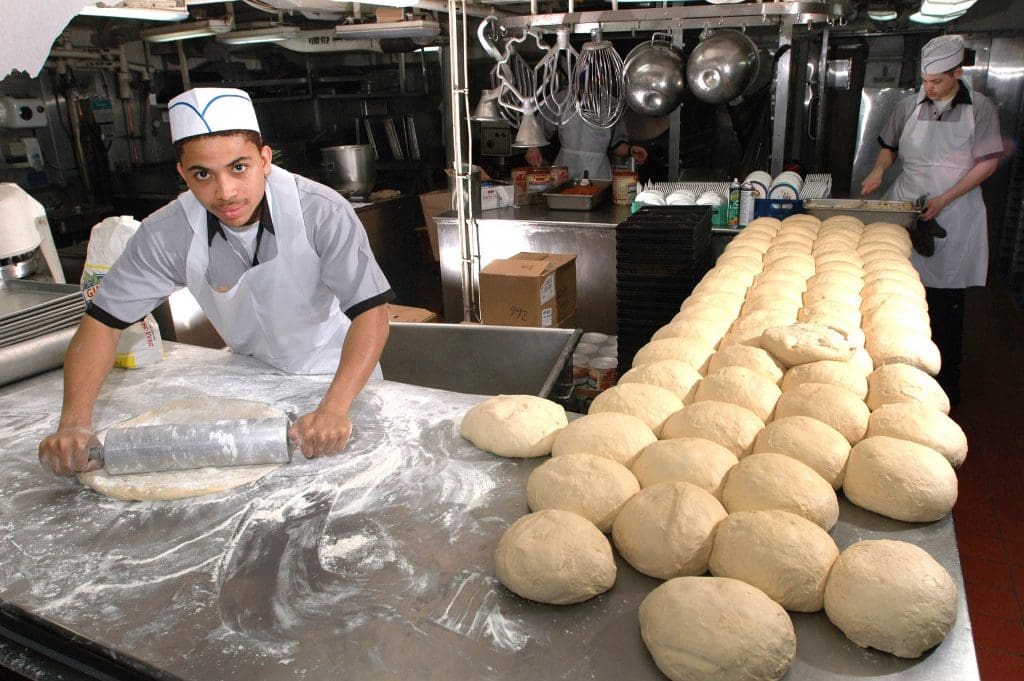 baker rolling out bread dough